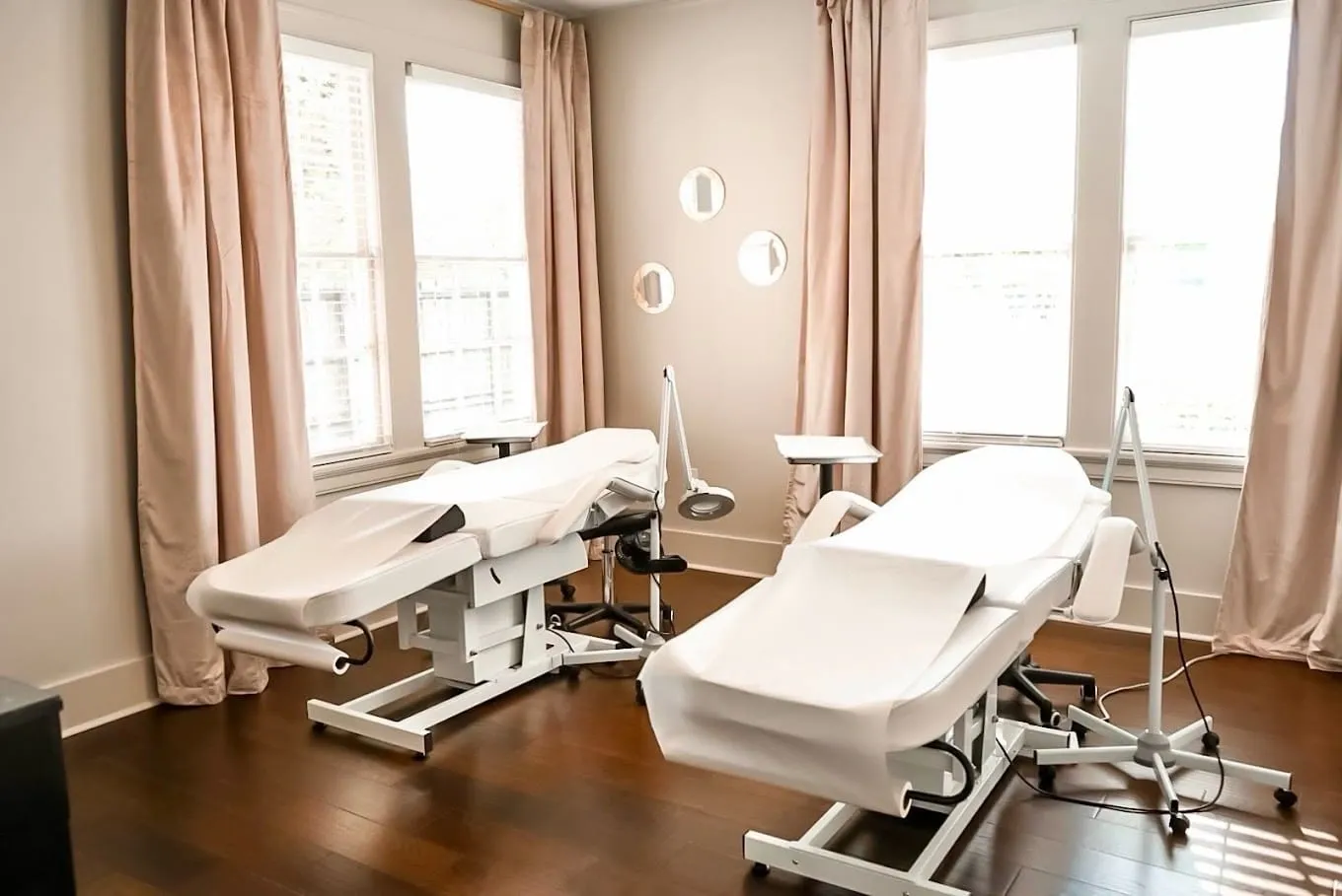 A room with two white tables and pink curtains